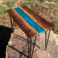 Handmade walnut epoxy river accent table with vibrant turquoise-blue resin center, natural wood grain, and black metal hairpin legs.